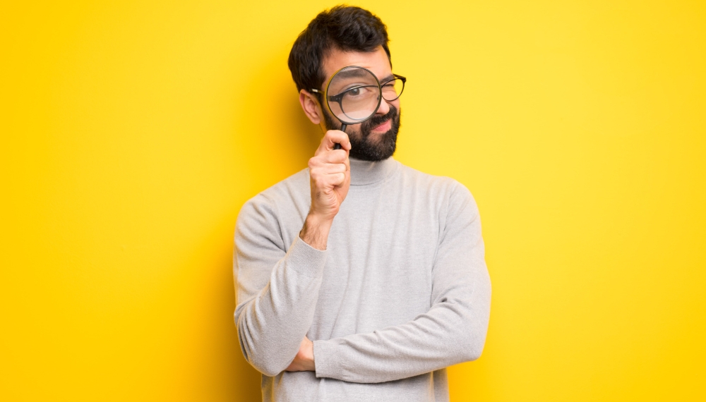 Homme qui tient une loupe au niveau de son oeil