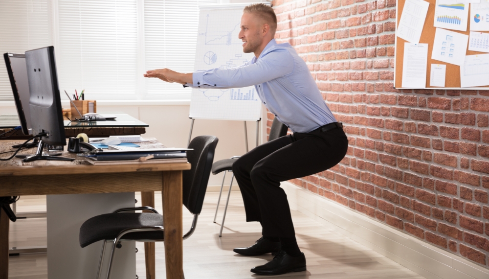 Homme qui fait des flexions devant son bureau de travail