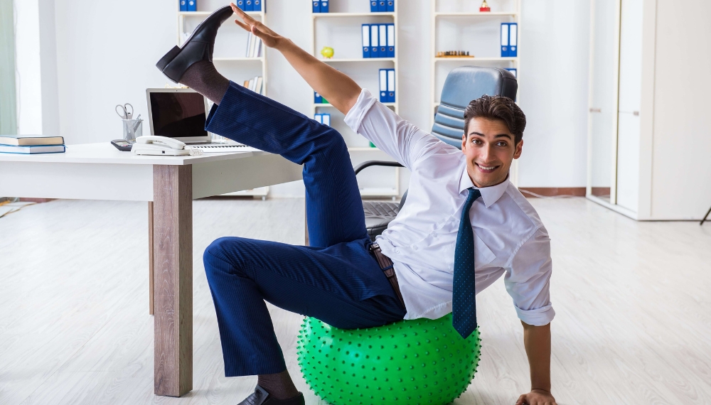 Homme qui s'étire sur une boule de gym au travail