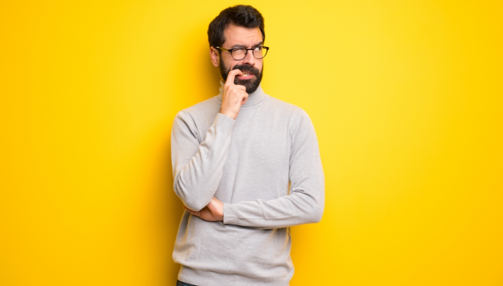 Homme qui se mord le doigt et qui est contemplatif sur un fond jaune