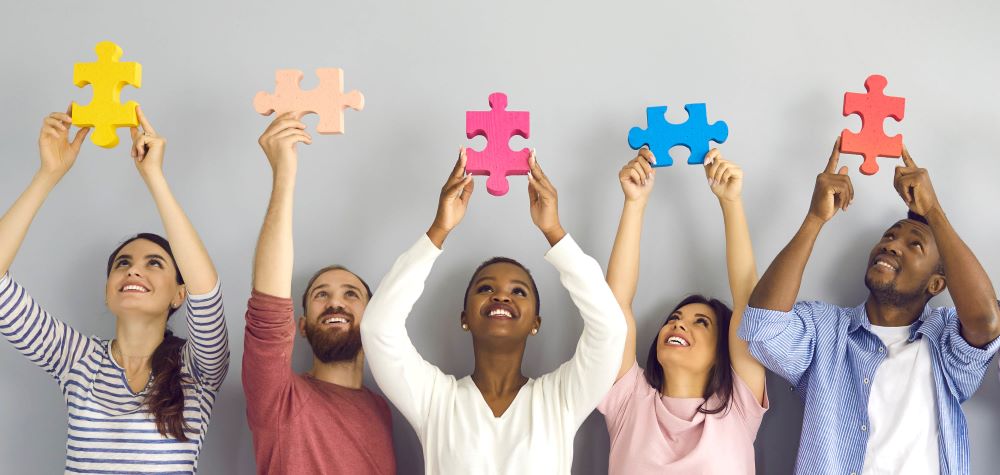 5 personnes qui regardent et tiennent un morceau de puzzle au dessus de leur tête