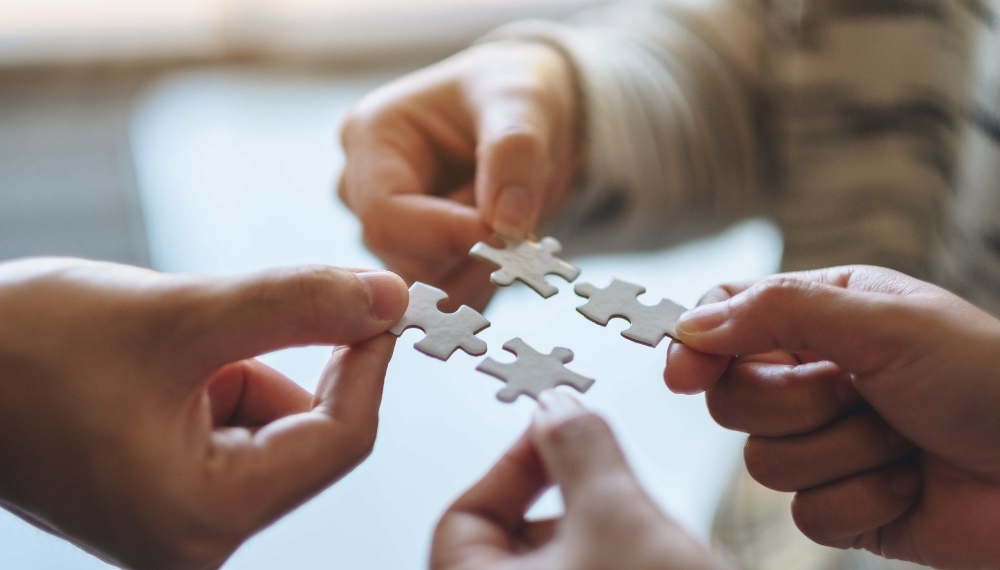 Quatre personnes tiennent chacun une pièce de puzzle